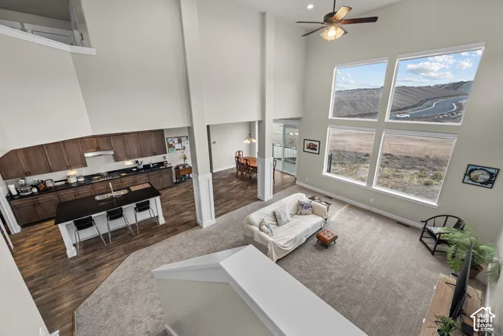 Open-concept interior with vaulted ceilings, large multi-pane windows, dark wood-finish cabinetry, a kitchen island with dark countertops, and wood-finish flooring