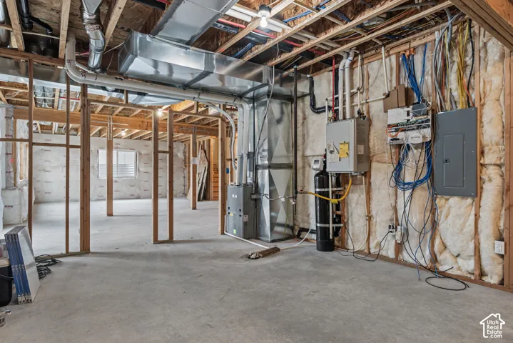 Unfinished lower level featuring exposed wood framing, concrete flooring, dedicated HVAC system, water filtration unit, and electrical service panel