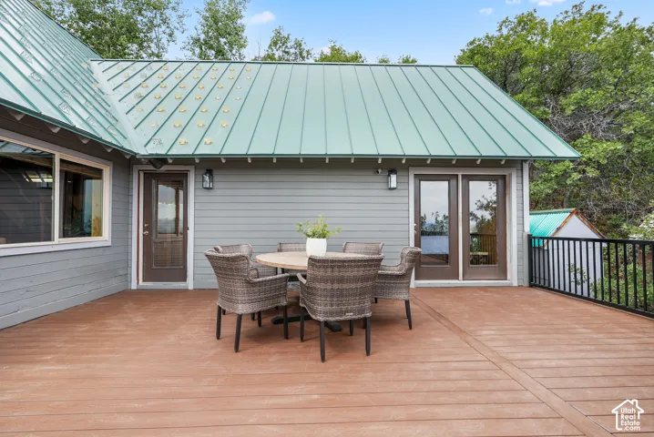 Expansive composite deck featuring a metal roof, horizontal siding, double glass-panel doors, and a black metal railing
