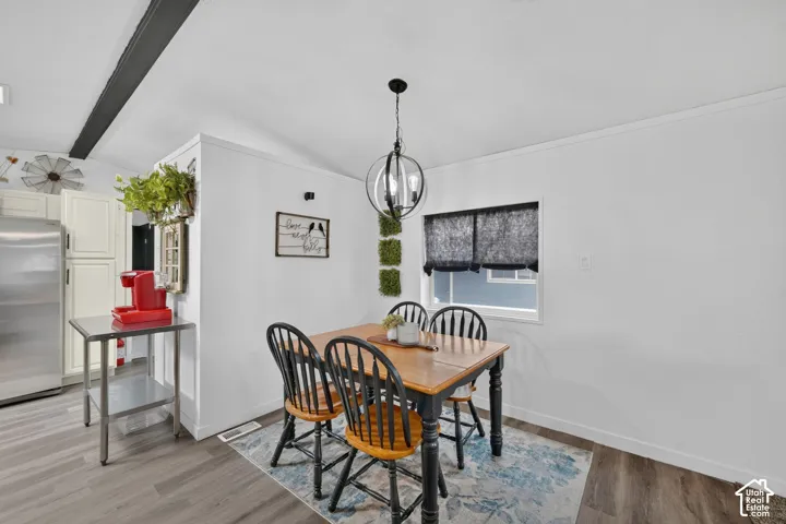 Wood-finish flooring, exposed structural beam, spherical multi-light pendant fixture, and white cabinetry