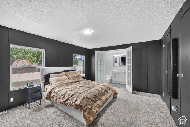 Bedroom featuring dark-toned walls, carpeting, dual-pane windows, and a set of white French doors