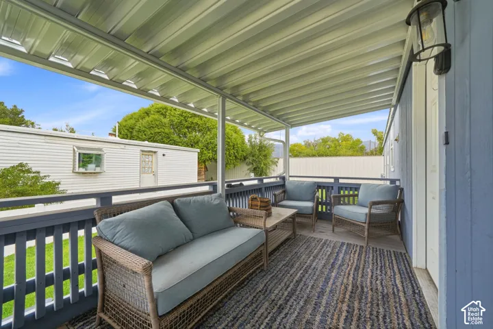 Covered porch featuring a corrugated metal roof, blue-painted wood railings, and a wall-mounted exterior light fixture