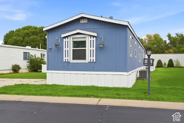 Blue exterior siding featuring white trim, a gabled roofline, decorative window shutters, and a post-mounted exterior light fixture