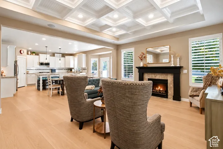 Coffered ceiling featuring recessed lighting, fireplace with a contrasting mantle, wood-finish flooring, and white plantation shutters