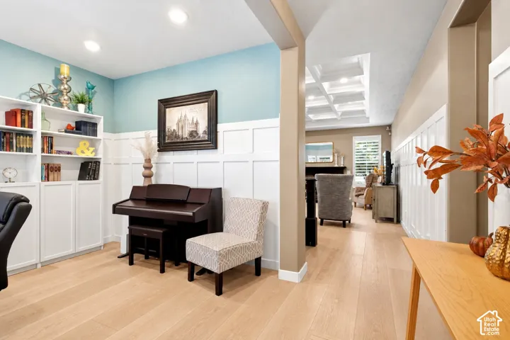 Wood-finish flooring, crisp white board-and-batten wall detailing, built-in floor-to-ceiling cabinetry, recessed lighting, and a coffered ceiling
