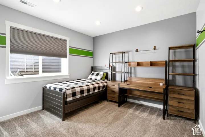 Neutral-toned interior space featuring recessed ceiling lighting, wall-to-wall carpeting, and a window with a pleated shade