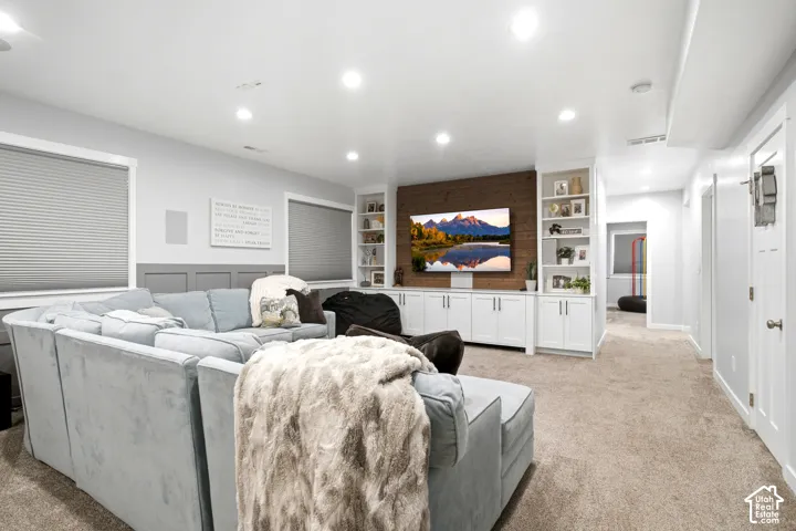 Custom built-in cabinetry featuring white shaker-style doors and open shelving, wood-plank accent wall, recessed lighting, and wall-panel wainscoting