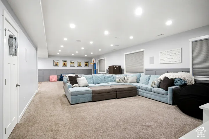 Interior space featuring neutral wall-to-wall carpeting, recessed ceiling lighting, and half-height decorative wall paneling