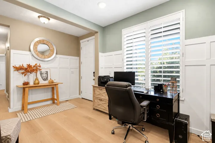 Interior space featuring white board-and-batten wainscoting, light-toned wood-finish flooring, and white plantation shutters