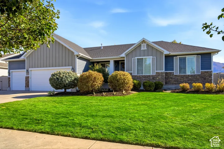 Single-level exterior featuring a multi-textured facade of vertical board-and-batten siding, horizontal lap siding, and stone veneer accents, complete with a three-car garage and concrete driveway