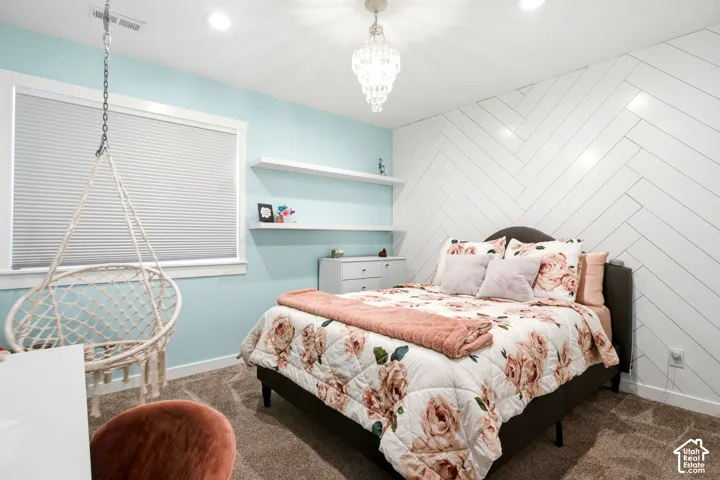 Herringbone pattern accent wall, recessed lighting, crystal-style pendant fixture, and white built-in floating shelves