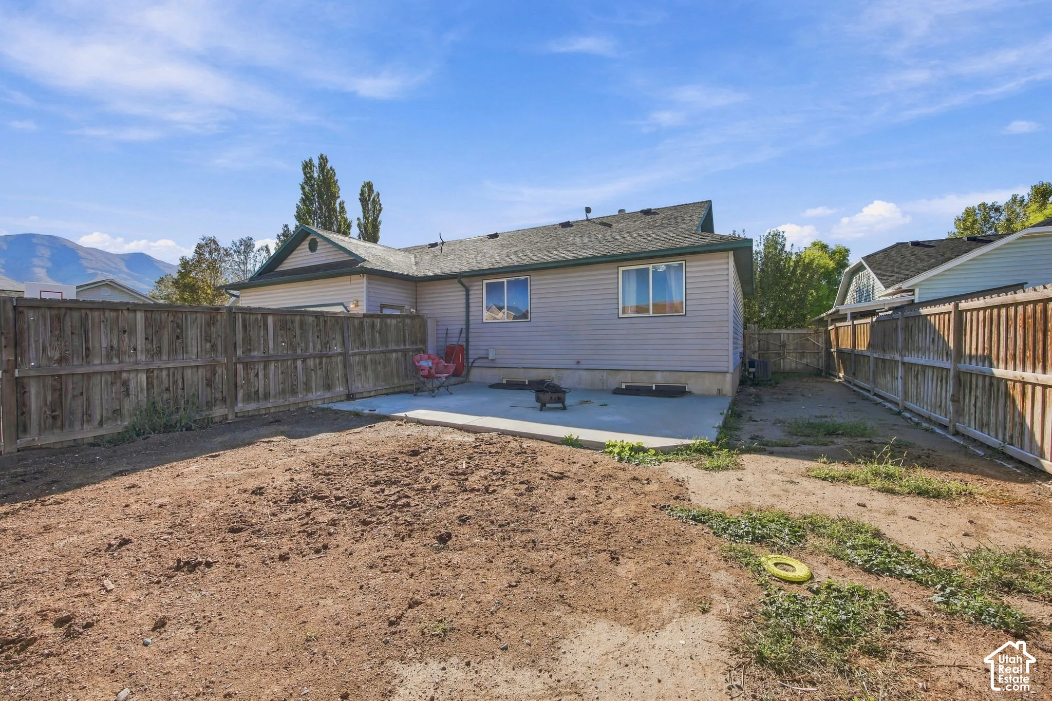 Backyard featuring a concrete patio, wood privacy fencing, and mountain scenery