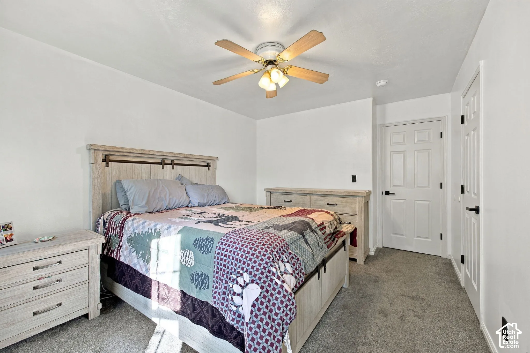 Neutral-toned interior featuring wall-to-wall carpeting, a ceiling fan with integrated lighting, and two six-panel doors with matte black hardware