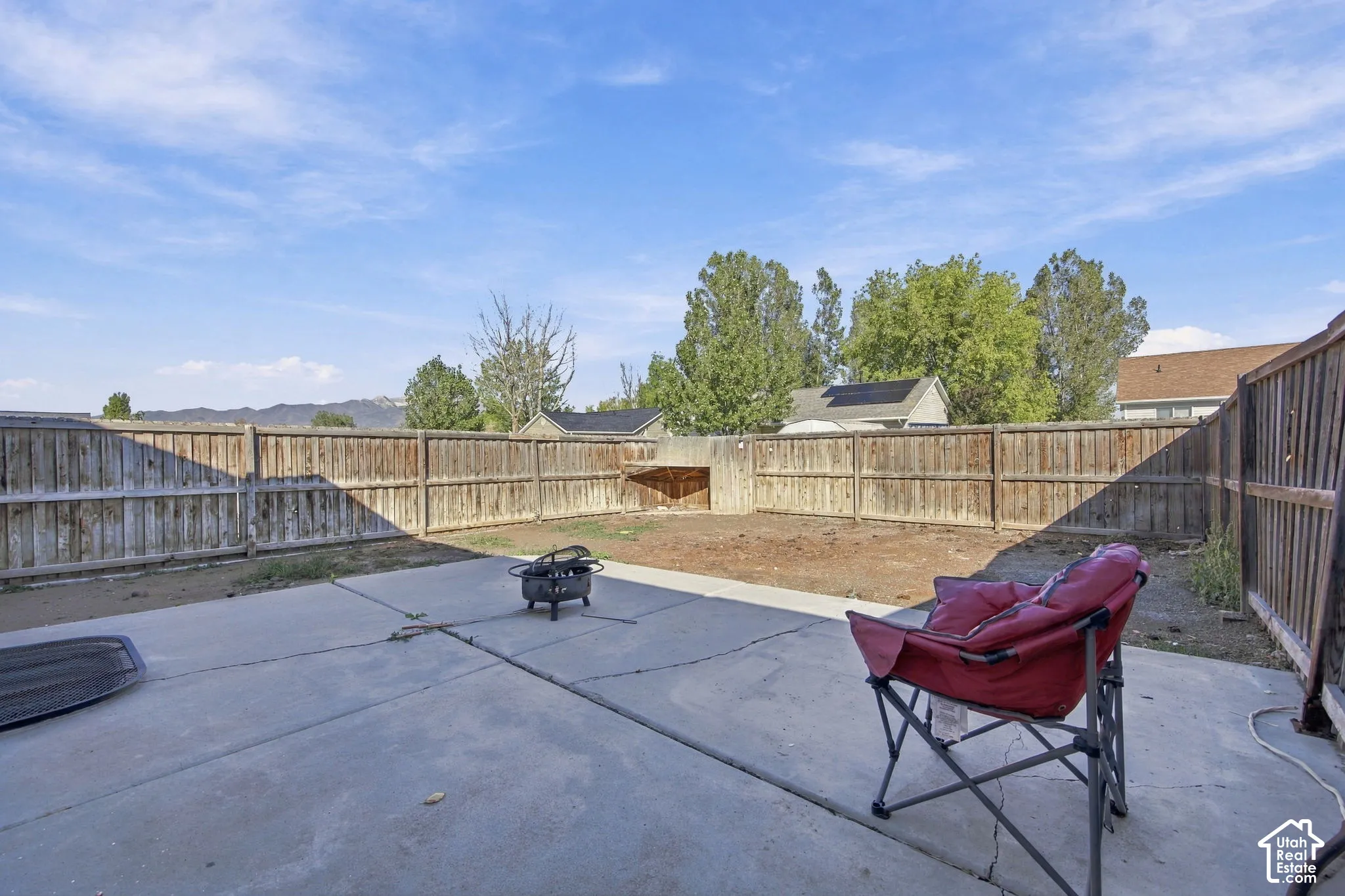 Backyard featuring a concrete patio, perimeter wood fencing, and mountain backdrop