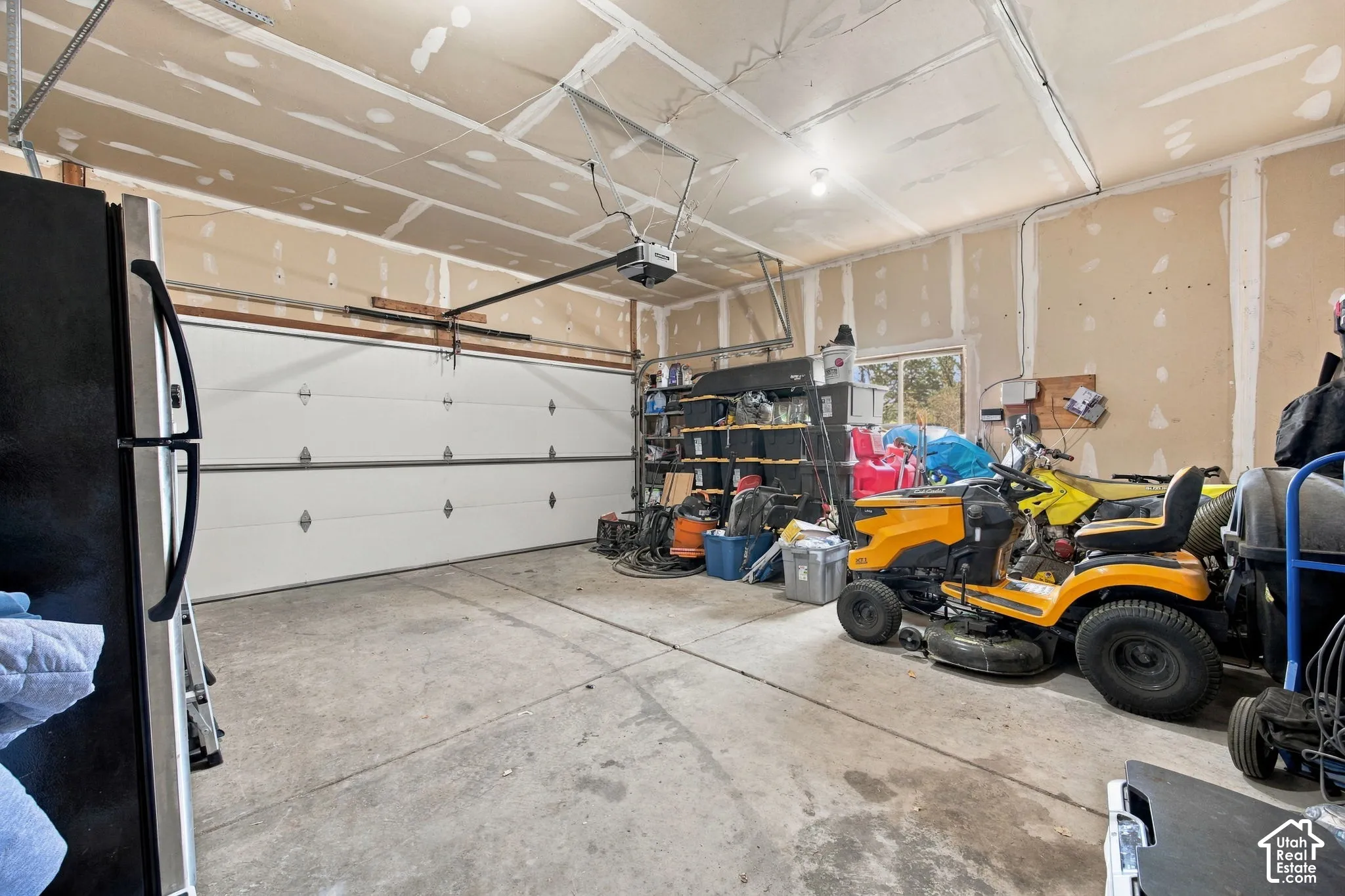Multi-car garage featuring a concrete floor, automated overhead door, and ceiling-mounted garage door opener