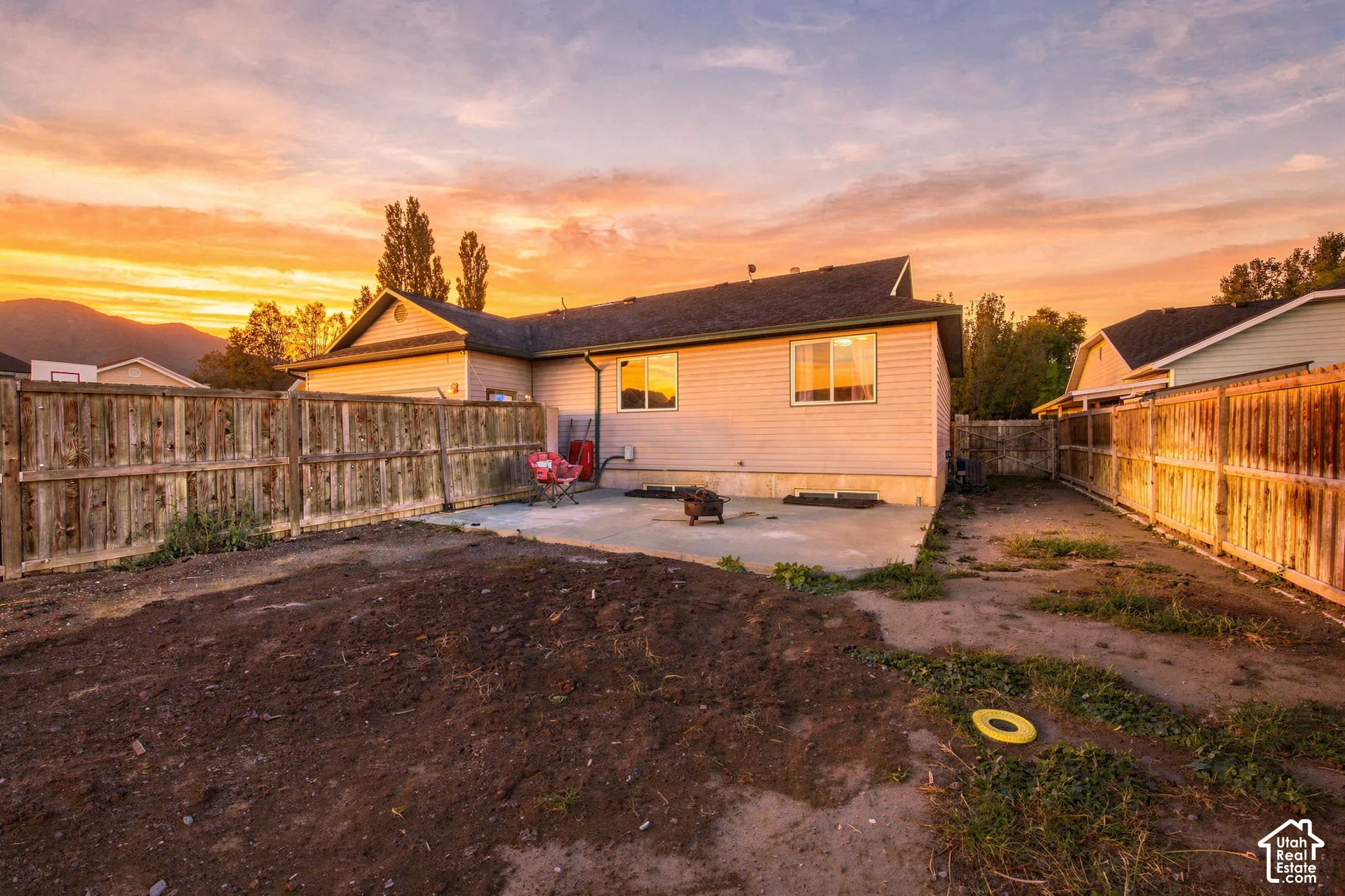 Rear exterior featuring a concrete patio, horizontal siding, and a wooden privacy fence
