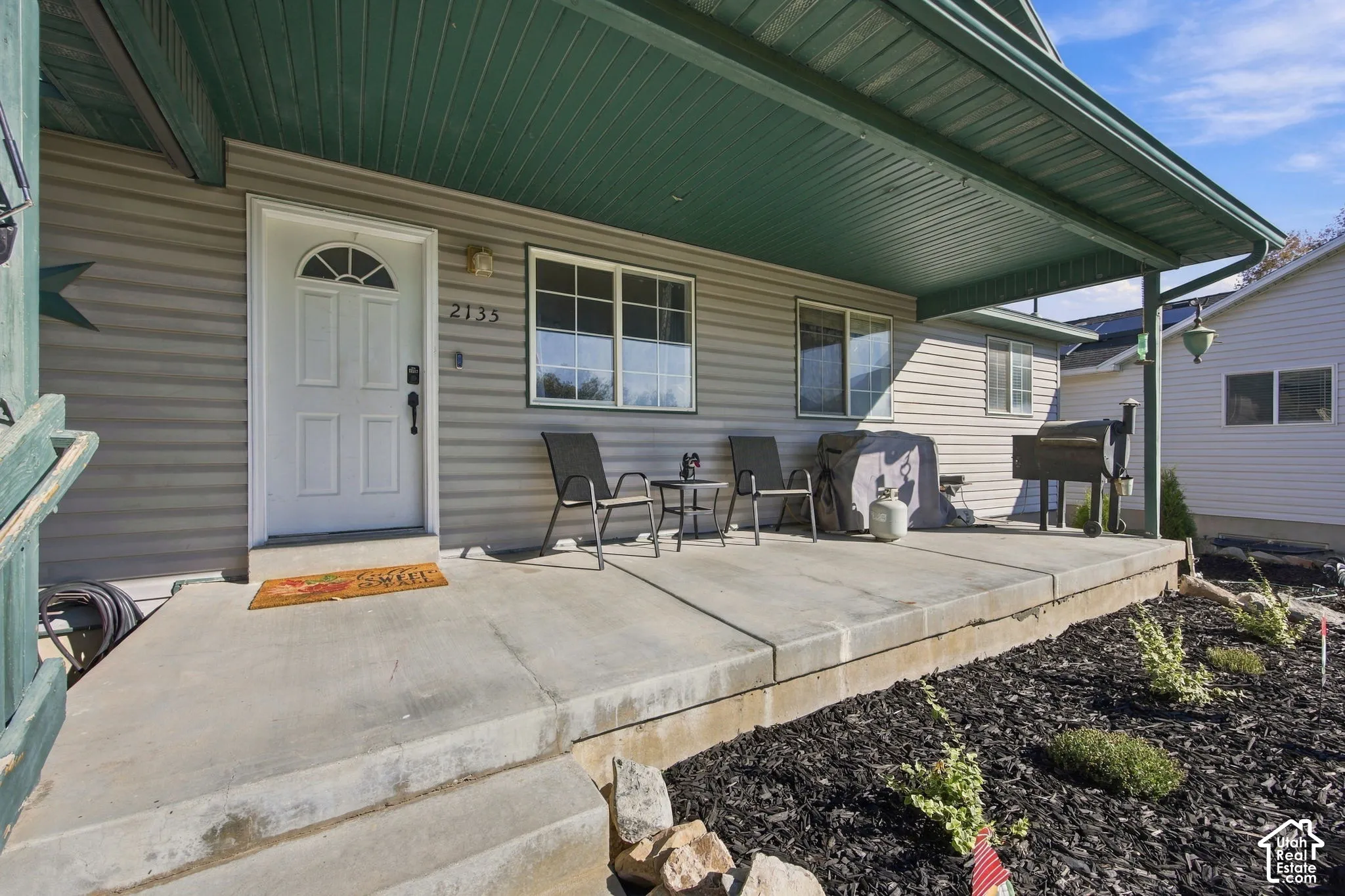 Covered front porch featuring concrete flooring, horizontal siding, and mulched landscaping beds