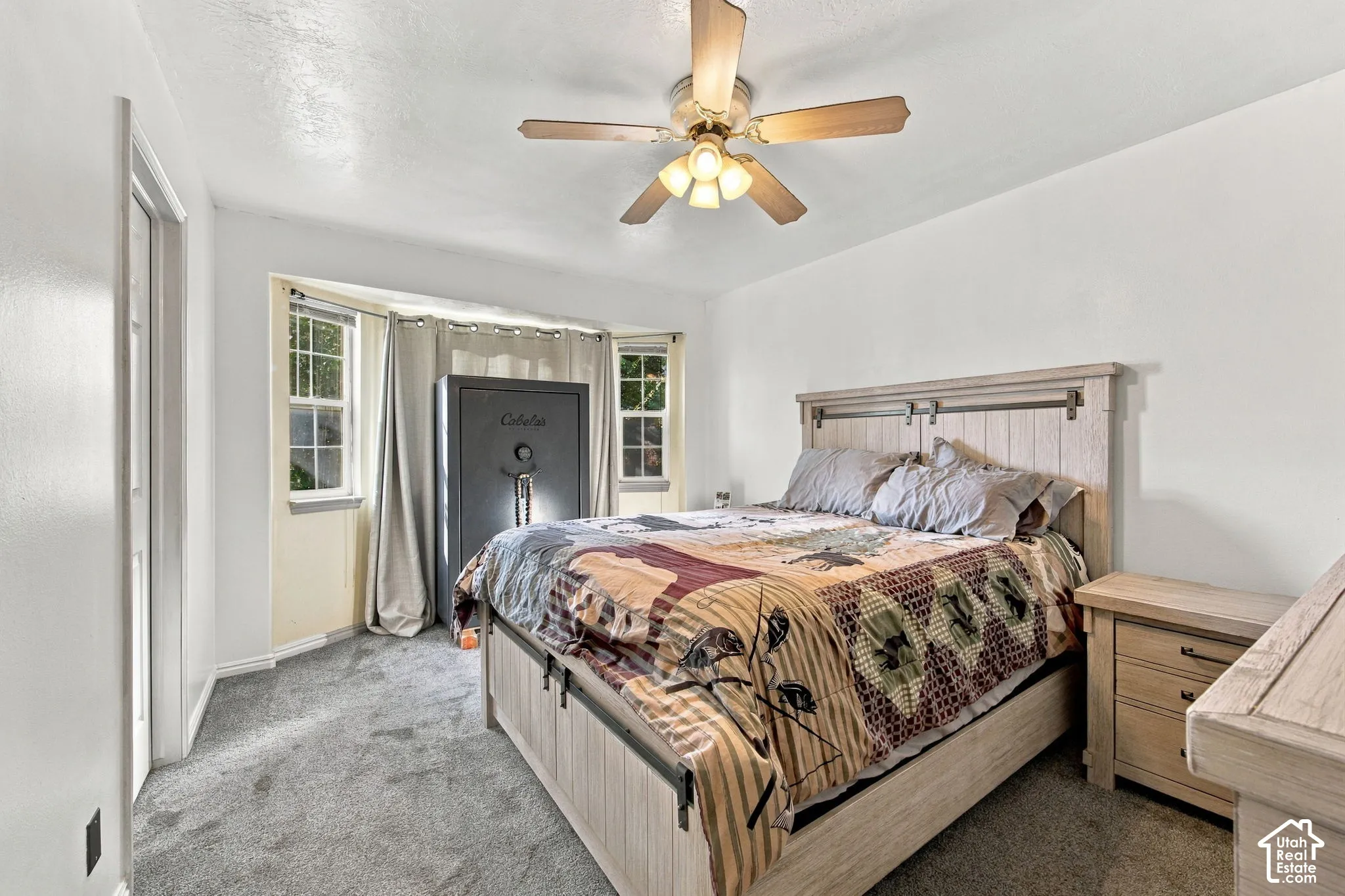Neutral-toned carpeting, multi-pane bay window, and ceiling-mounted light fixture with a fan