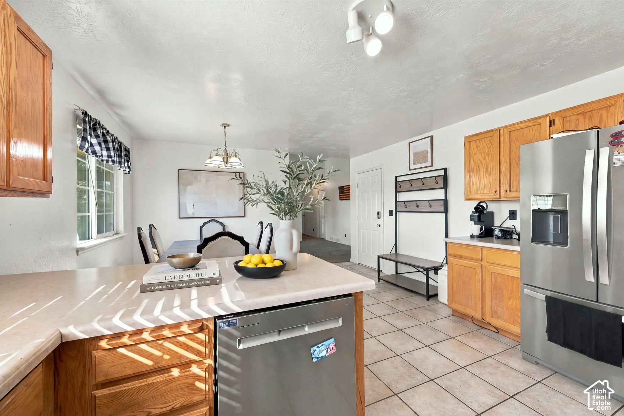 Kitchen featuring wood cabinetry, stainless steel appliances, neutral countertop, and tile flooring