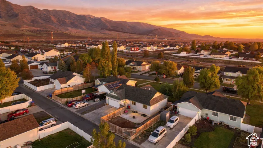 Aerial perspective featuring residential lots, solar panel arrays, paved driveways, and expansive mountain scenery