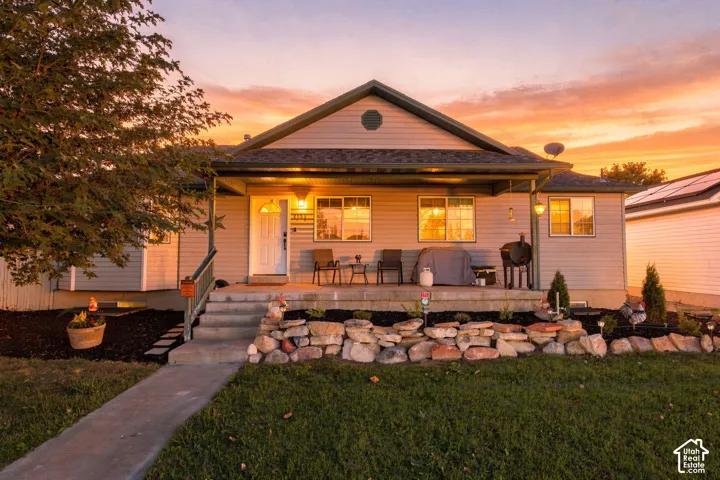 Single-story residence featuring horizontal siding, a covered front porch, concrete steps, and a decorative natural stone retaining wall