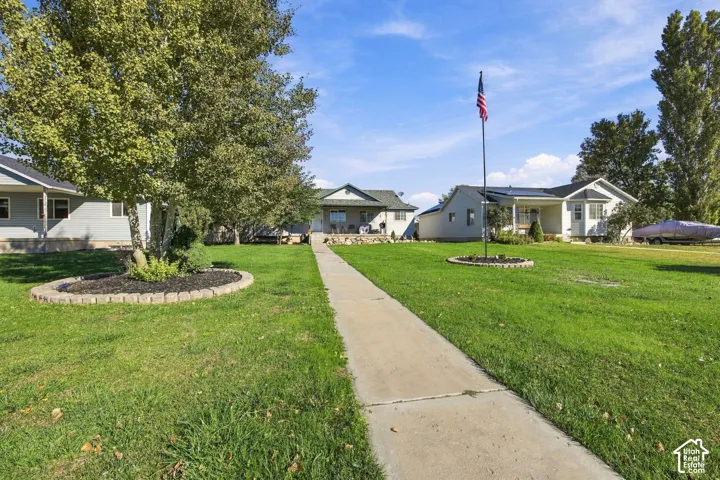 Front yard featuring a concrete walkway, established landscaping with circular stone edging, and mature trees