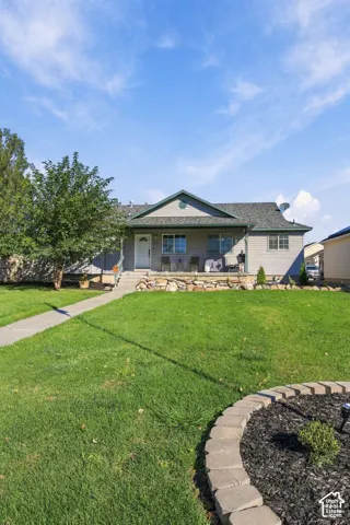 Single-story exterior featuring horizontal siding, a covered front porch, a stone retaining wall, and a concrete walkway