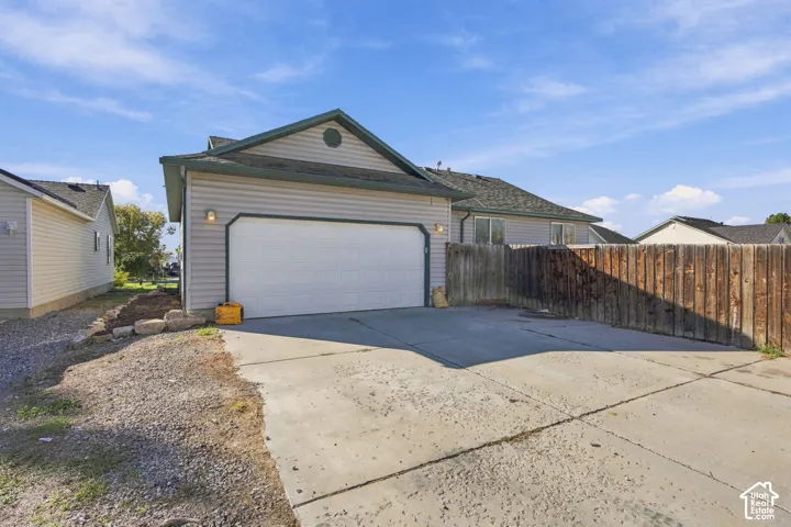 Attached two-car garage with horizontal siding, concrete driveway, and wooden privacy fencing
