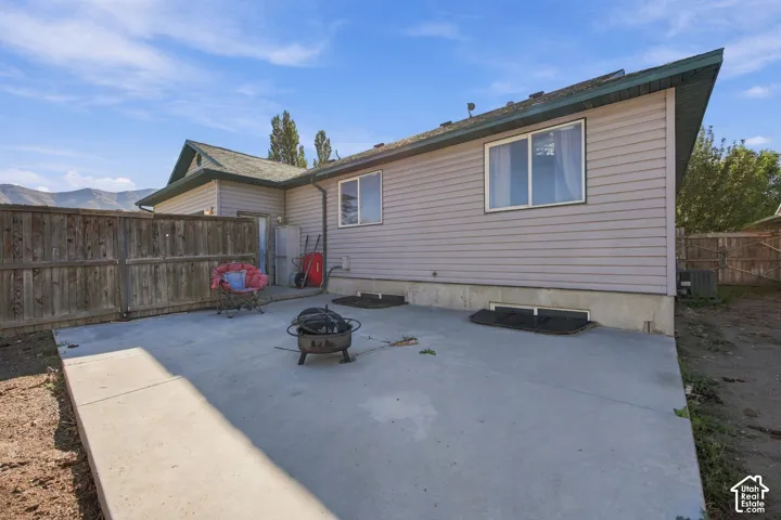 Rear exterior featuring horizontal vinyl siding, concrete patio, and wood privacy fencing