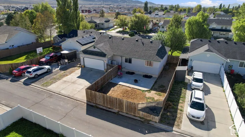 Single-level residence featuring an attached garage, roof-mounted solar panels, a concrete patio, and enclosed wooden fencing