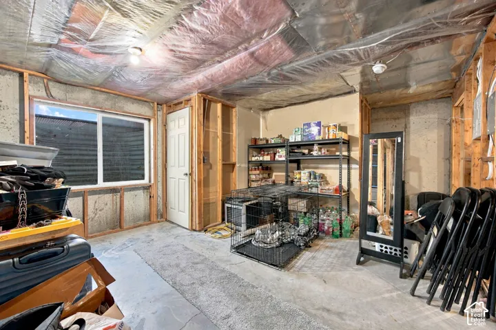 Unfinished lower level featuring exposed wood framing, concrete foundation walls, concrete flooring, and a sliding window with an egress well