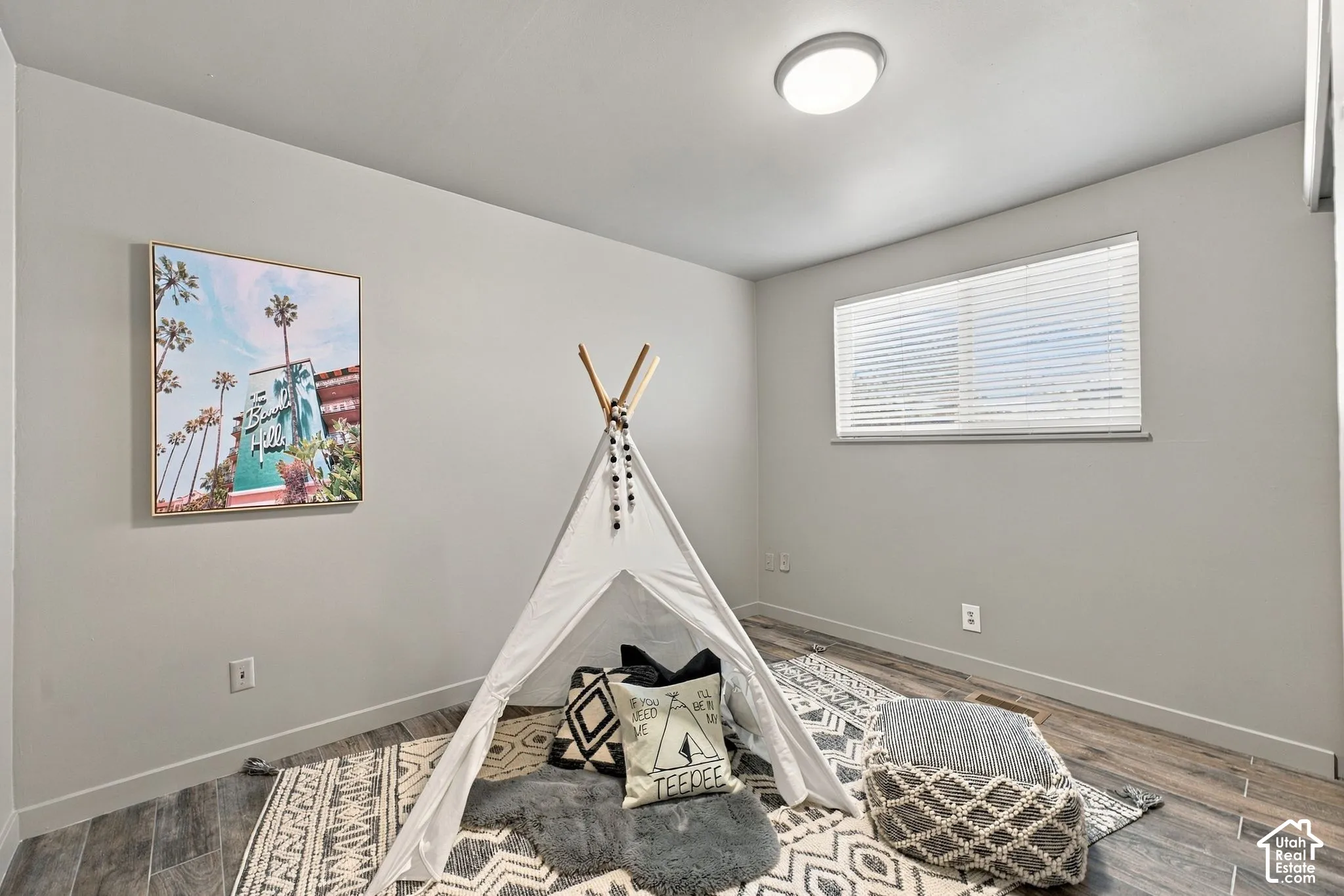 Neutral interior featuring wood-finish flooring, a flush-mount ceiling light, and a window with horizontal blinds