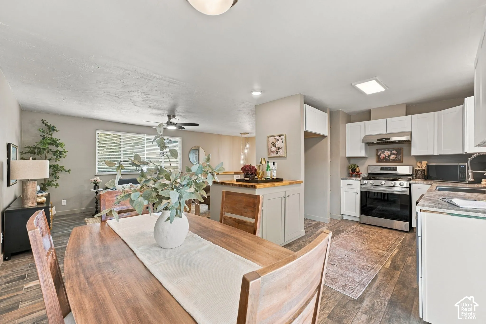 Kitchen featuring white cabinetry, stainless steel gas range, wood-finish flooring, and a center island with a wood countertop
