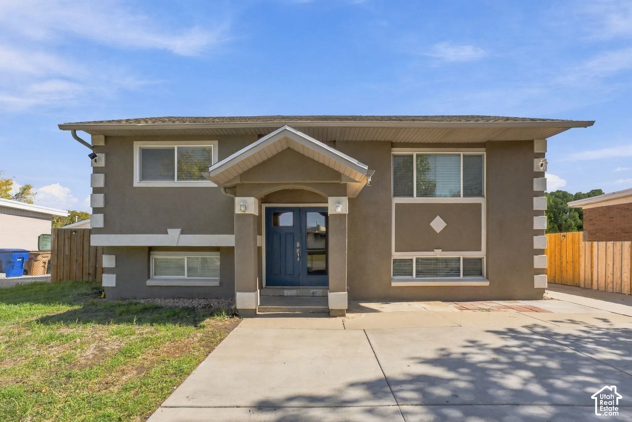 Split-level exterior featuring a covered front entryway, double-door entrance, concrete driveway, and white corner accents