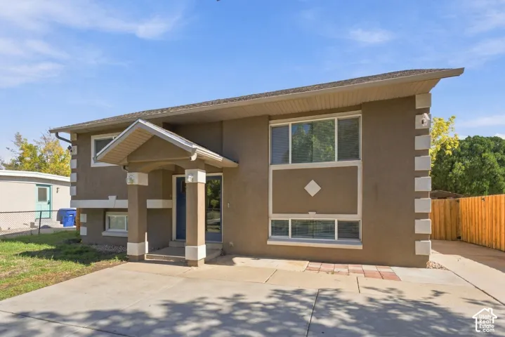 Two-story stucco exterior featuring contrast corner quoins, a covered entryway with structural columns, and a paved concrete driveway
