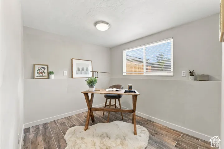Room featuring wood-finish tile flooring, neutral wall tones, a large horizontal window with integrated blinds, and a flush-mount circular ceiling light