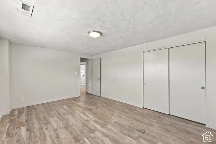 Wood-finish flooring, textured ceiling, flush-mount lighting, and dual sliding-door closet
