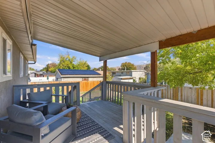 Covered wooden deck featuring horizontal railings, an expansive overhead roof structure, and wood-finish stairs