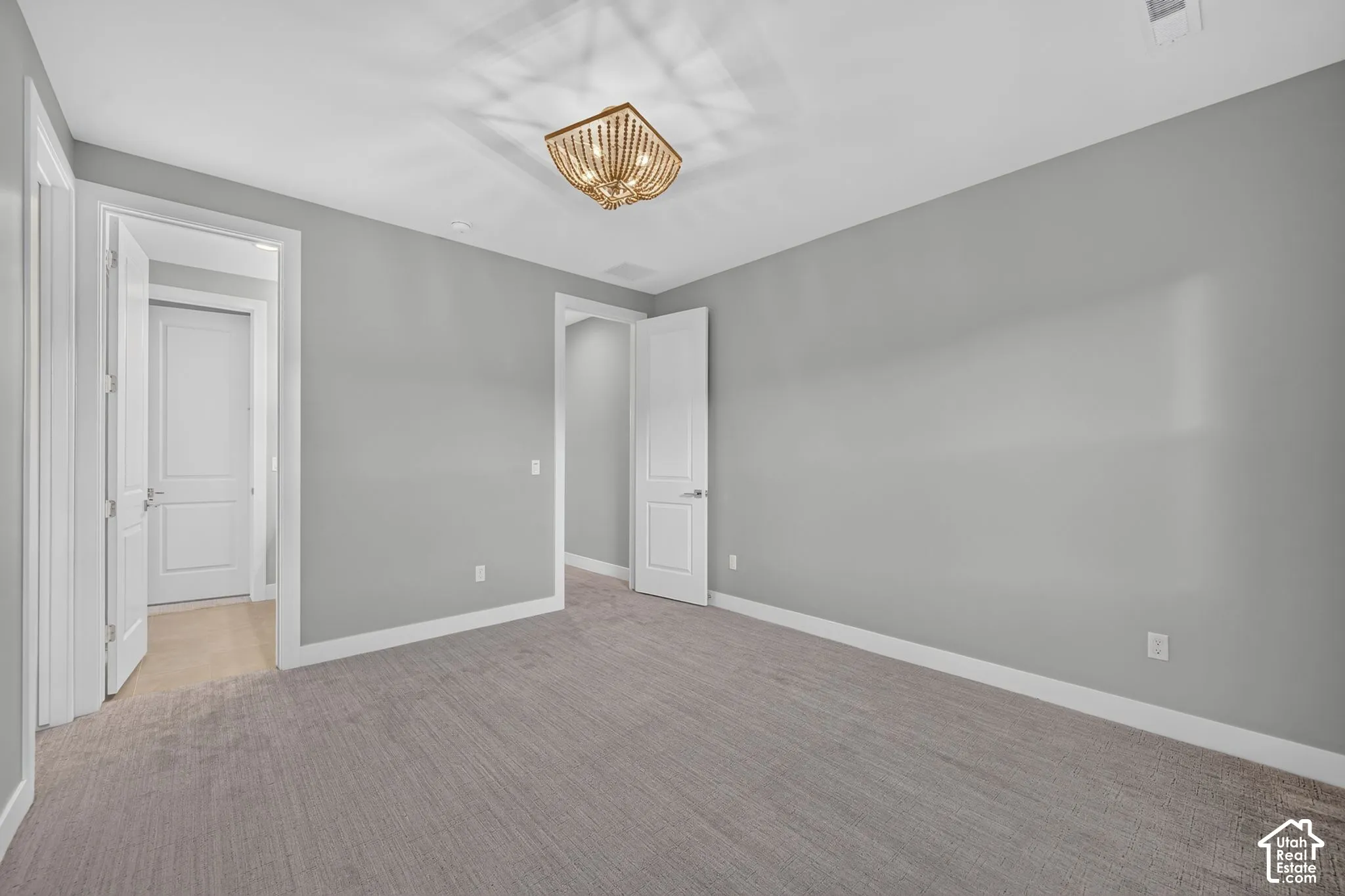 Neutral-toned interior space featuring wall-to-wall carpeting, two-panel interior doors, and a multi-light flush-mount ceiling fixture