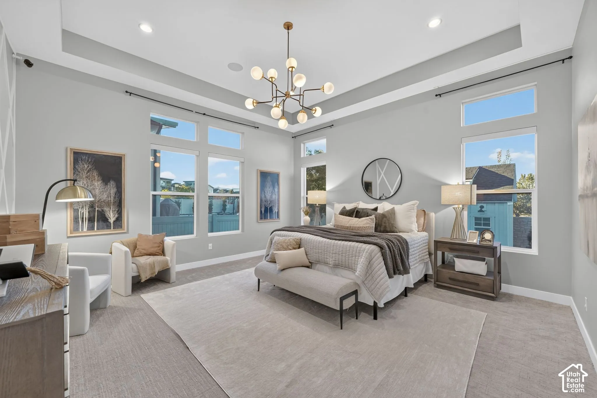 Spacious room featuring a tiered tray ceiling, multi-light modern chandelier, and oversized windows