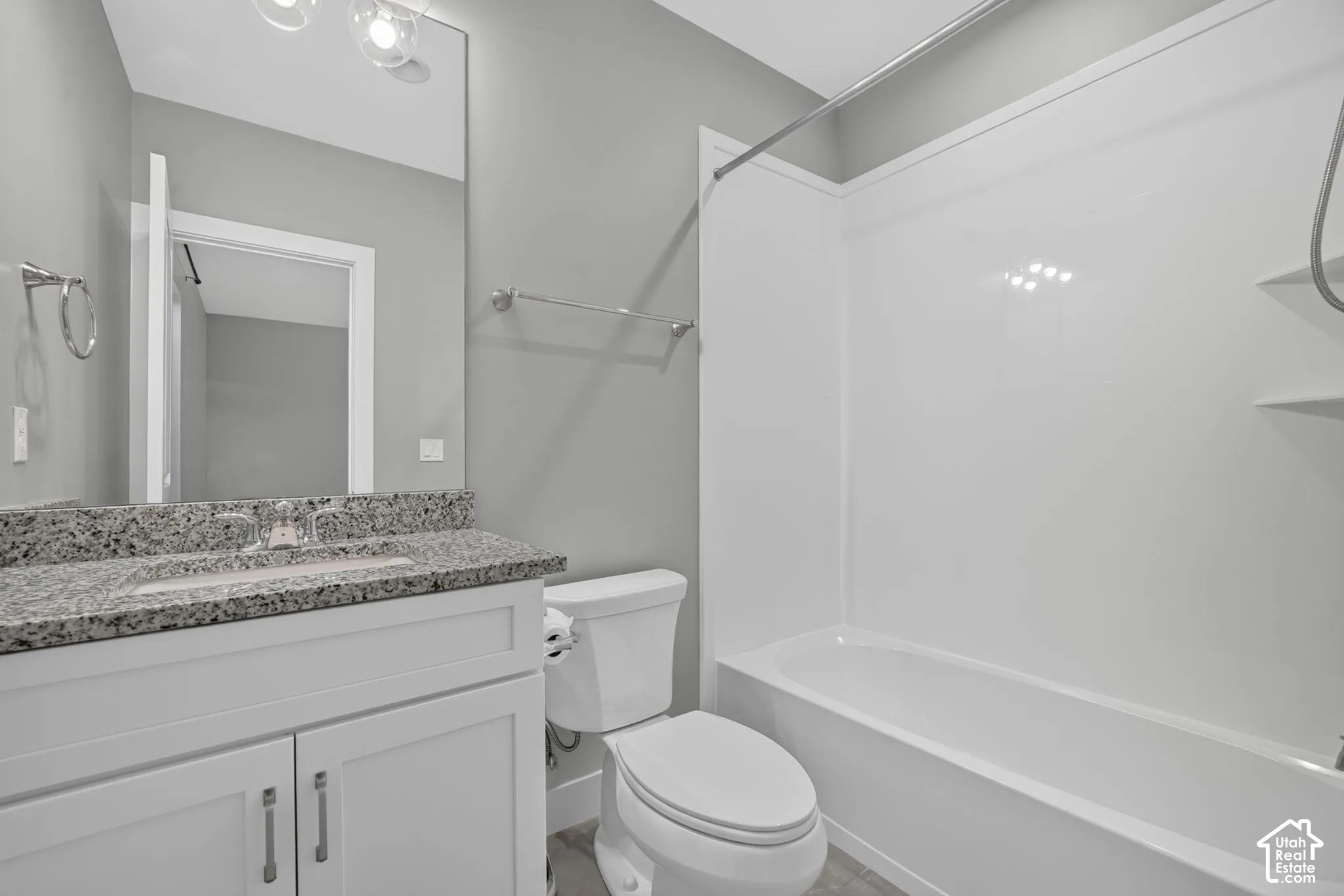 Bathroom featuring a vanity with stone-finish countertop, undermount sink, full-height wall mirror, and a tub-shower combination with integrated shelving