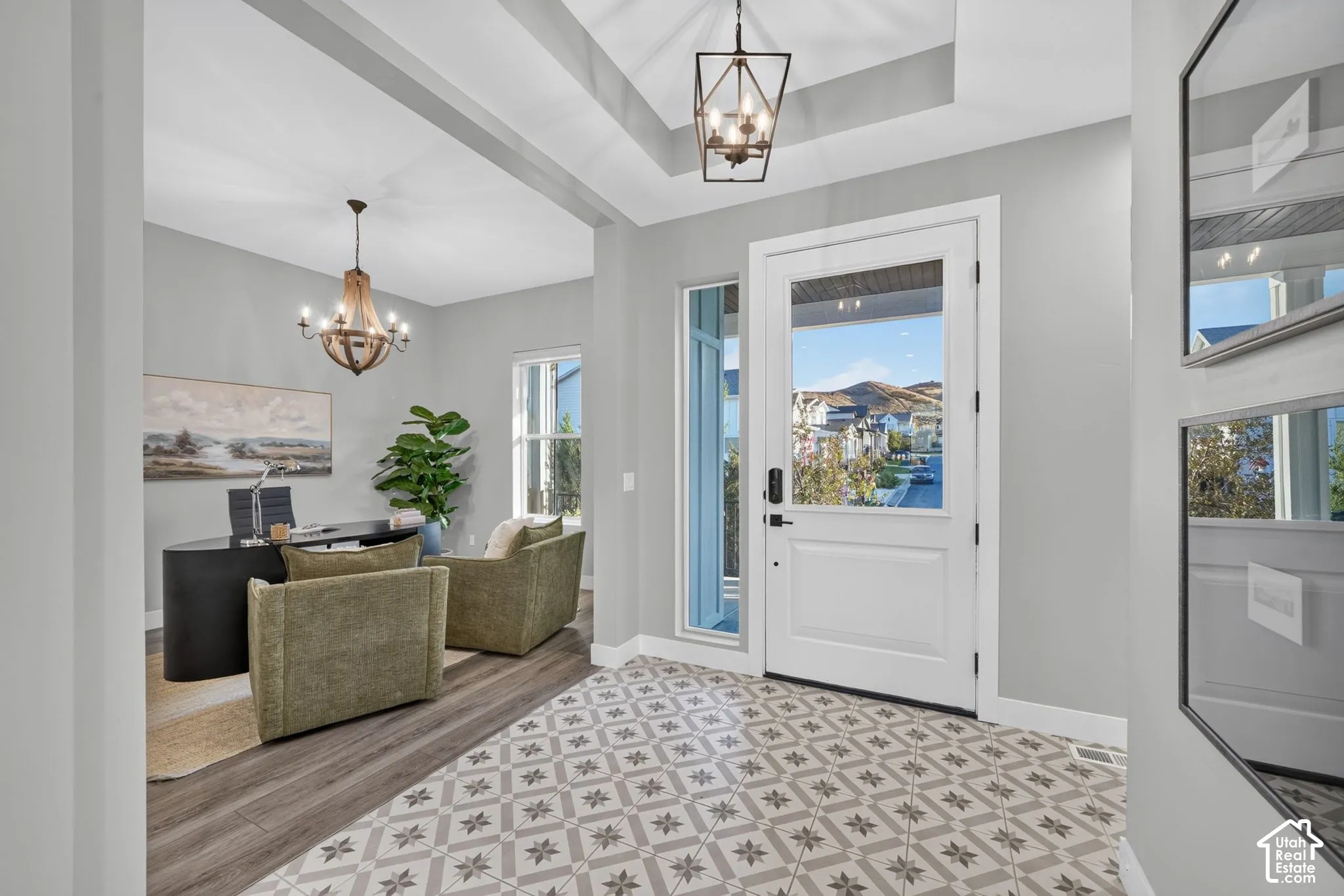 Entryway featuring patterned tile flooring, wood-finish flooring, a tray ceiling with a geometric lantern pendant, and a glass-paneled front door with a matching side light