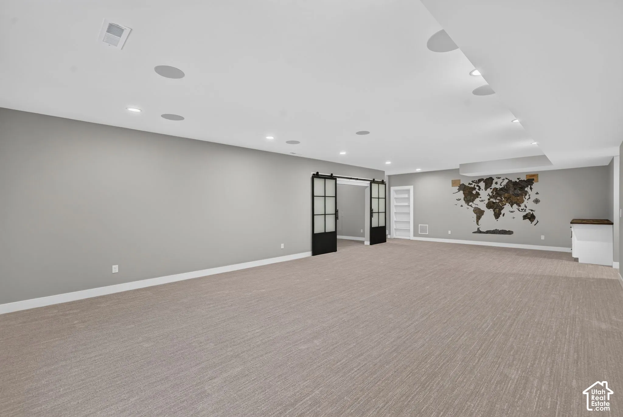 Open-concept space featuring recessed lighting, integrated ceiling speakers, carpeting, and black-framed sliding barn doors