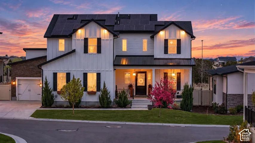 Modern farmhouse exterior featuring vertical siding, a metal roof accent, solar panels, and a covered front porch