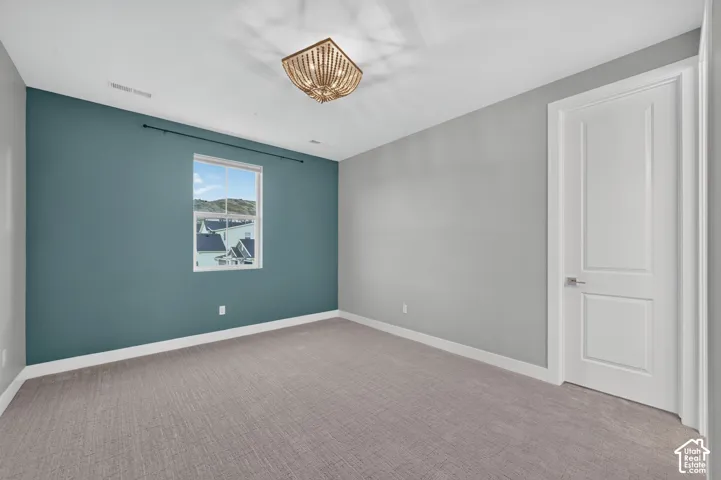Bedroom featuring wall-to-wall carpeting, a decorative beaded semi-flush mount light fixture, an accent wall, and a multi-panel interior door