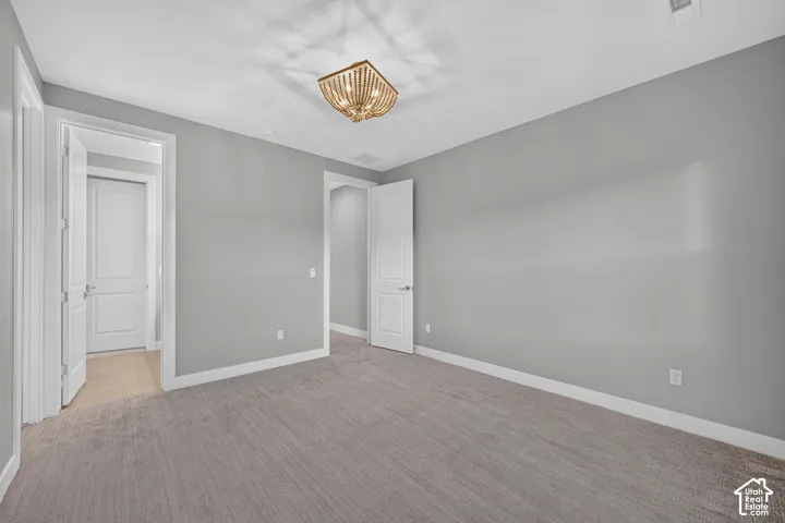 Neutral-toned interior space featuring wall-to-wall carpeting, two-panel interior doors, and a multi-light flush-mount ceiling fixture