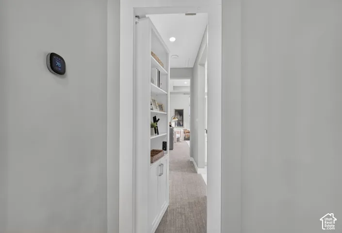 Built-in white cabinetry featuring a concealed door panel, smart home thermostat, and recessed ceiling lighting