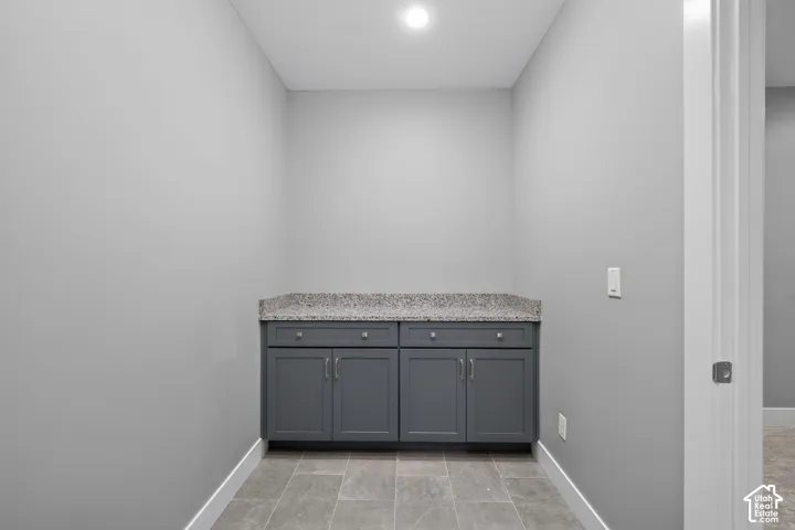 Built-in cabinetry featuring shaker-style doors, stone-surface countertop, dual drawers, and tiled flooring