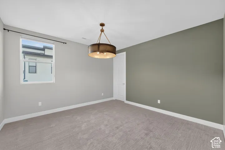 Room featuring neutral carpeting, an olive-tone accent wall, a drum-style pendant light fixture, and a single-pane window
