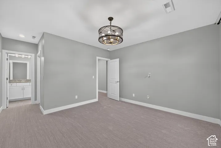 Neutral wall finish, carpeted flooring, multi-light circular drum chandelier, and two-panel interior doors